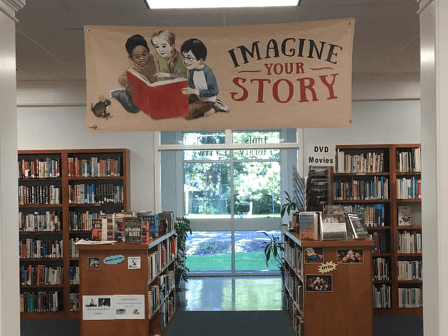 A banner of three children reading a giant red book hung over the DVD section of the Innis Library branch.