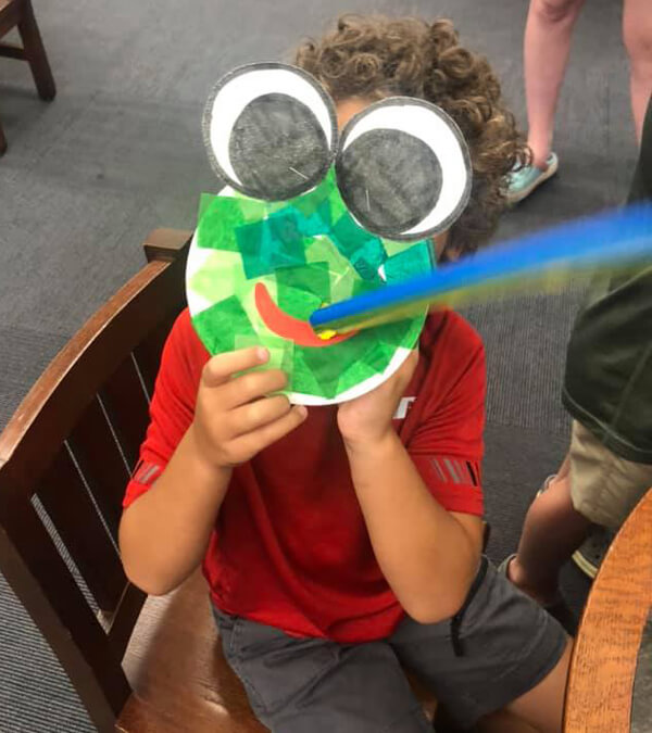 Child playing with a frog mask at one of Pointe Coupee's library events.