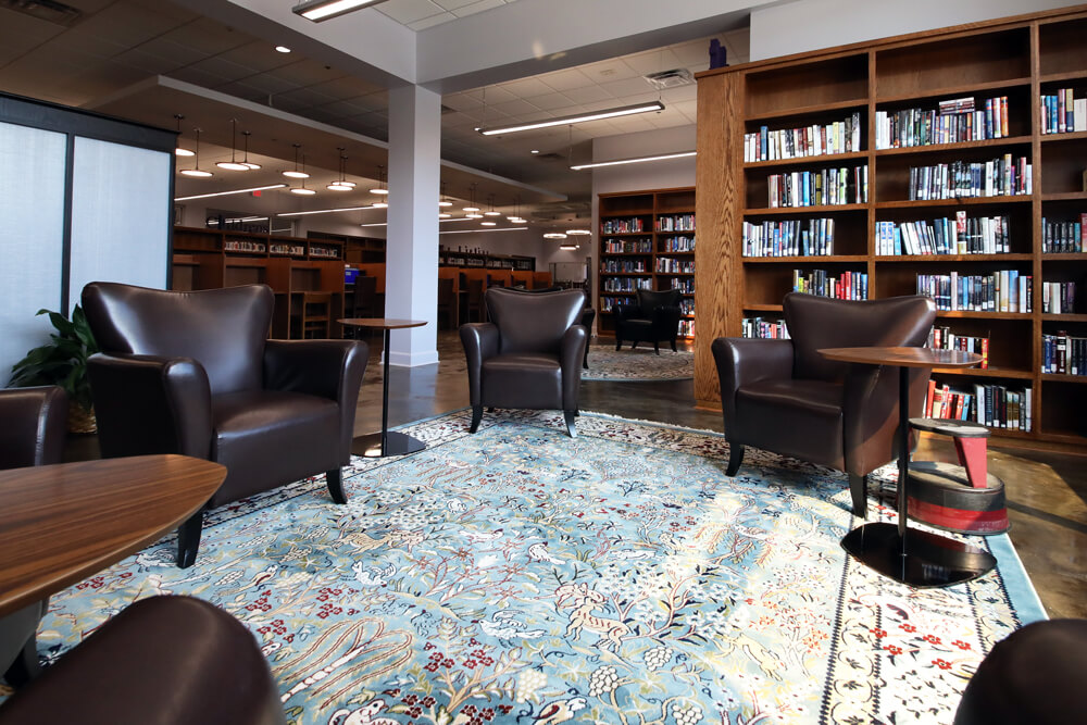 A cozy reading area in Livonia's public library branch with brown leather seats atop a vibrant rug.