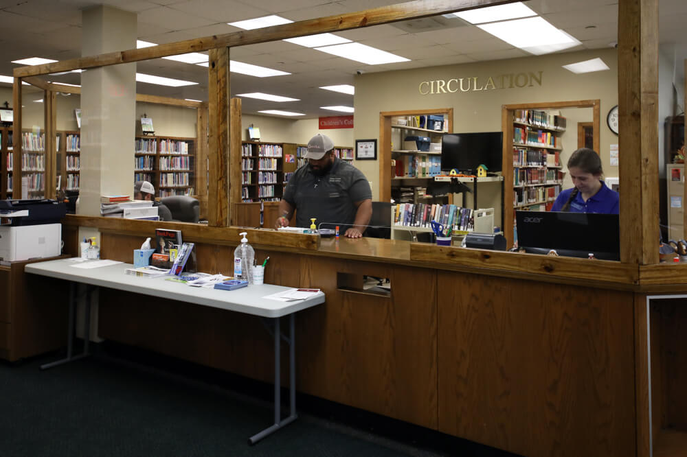 A couple of library circulation workers at the receptionist's desk of the Livonia public library branch.