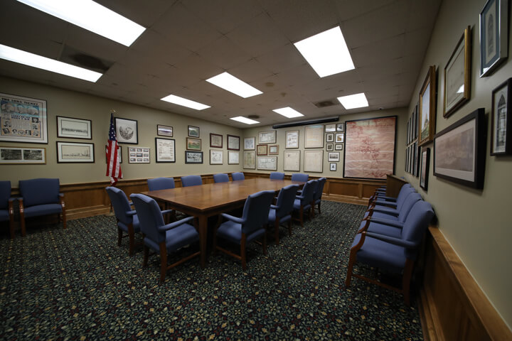 A Pointe Coupee library meeting room with a brown table at the center surrounded by many framed photographs and documents.