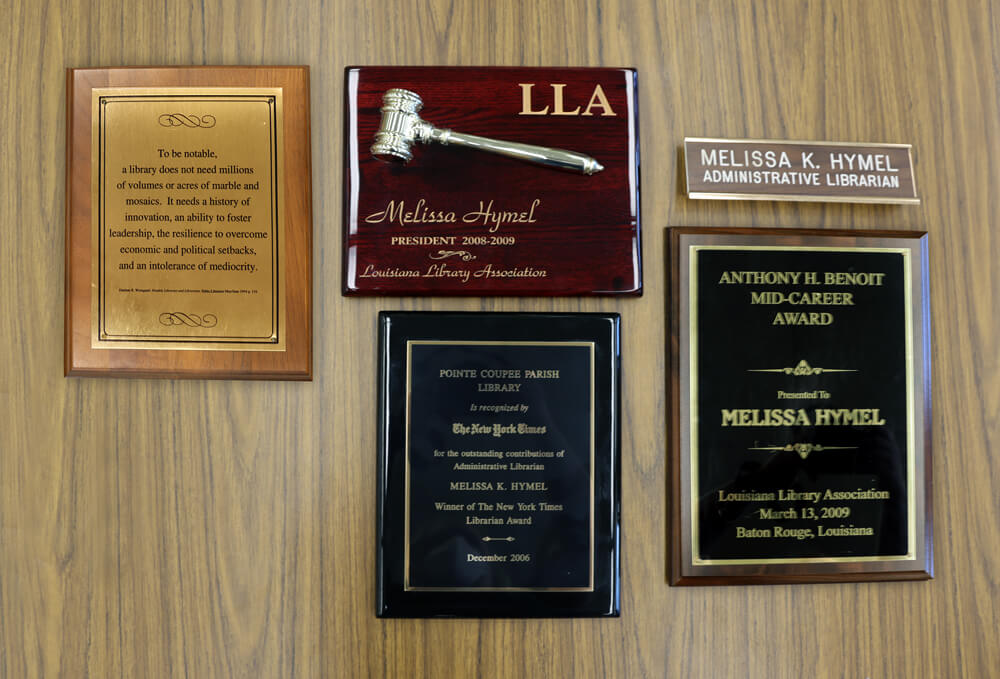 Various plaques awarded to Melissa Hymel, the Pointe Coupee Parish Library director, listing her many achievements.