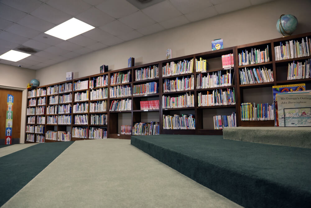 Carpeted staircase in front of several bookshelves at the Point Coupee Parish Library New Roads branch.